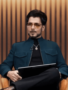 अनुपम मित्तल गहरे रंग का जैकेट और धूप का चश्मा पहने कुर्सी पर बैठकर बातचीत करते हुए।